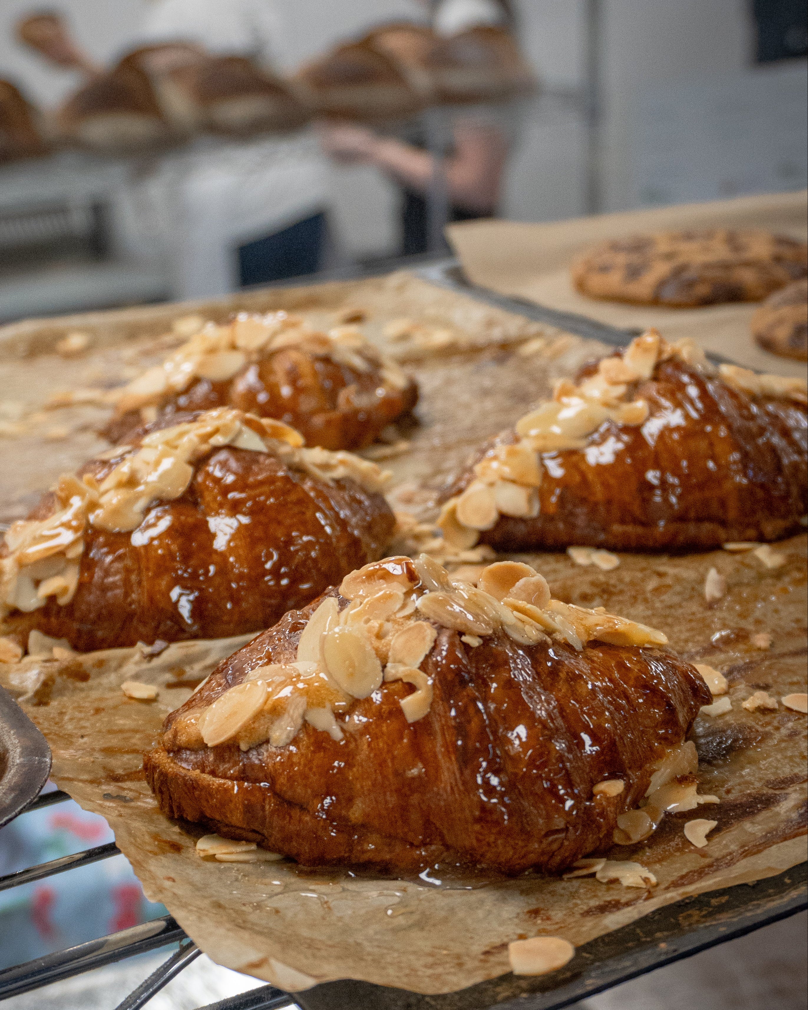 Baked pastries with almonds on a baking tray in a bakery setting
